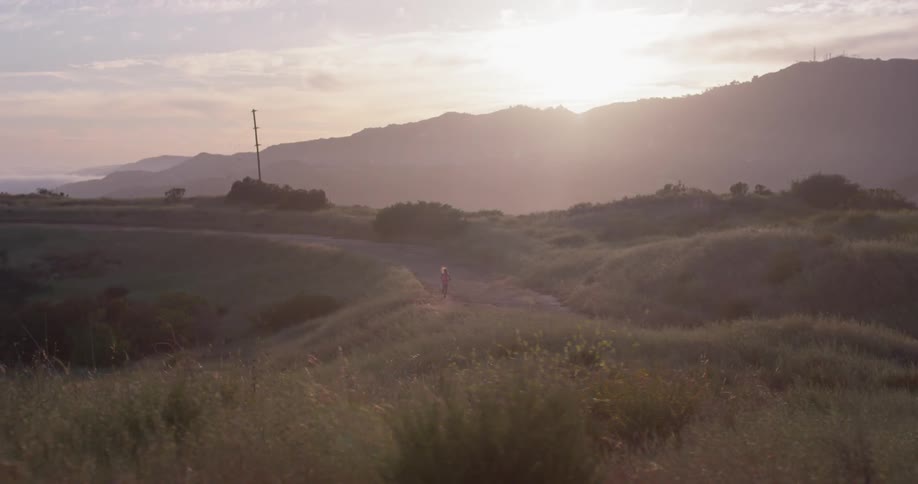 A woman jogs in a rural area at sunset