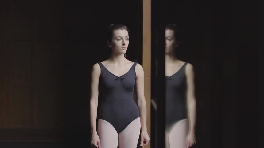 A woman wearing dance clothes looks out the window