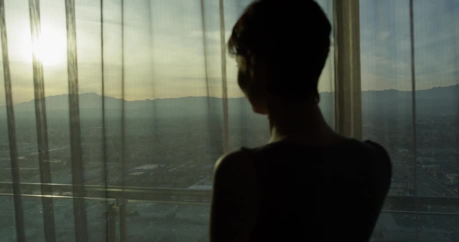Woman talks on a phone while looking out a window
