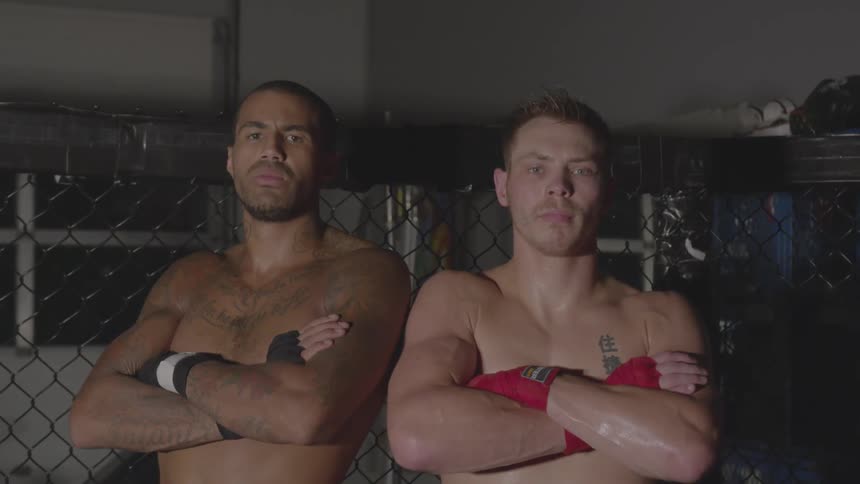 Two sweaty men stand together looking angry