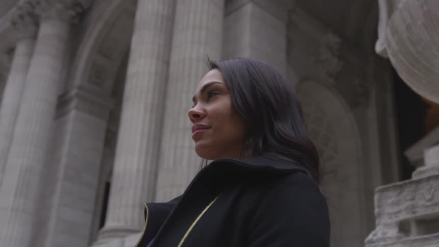 A woman stands in front of a large stone building