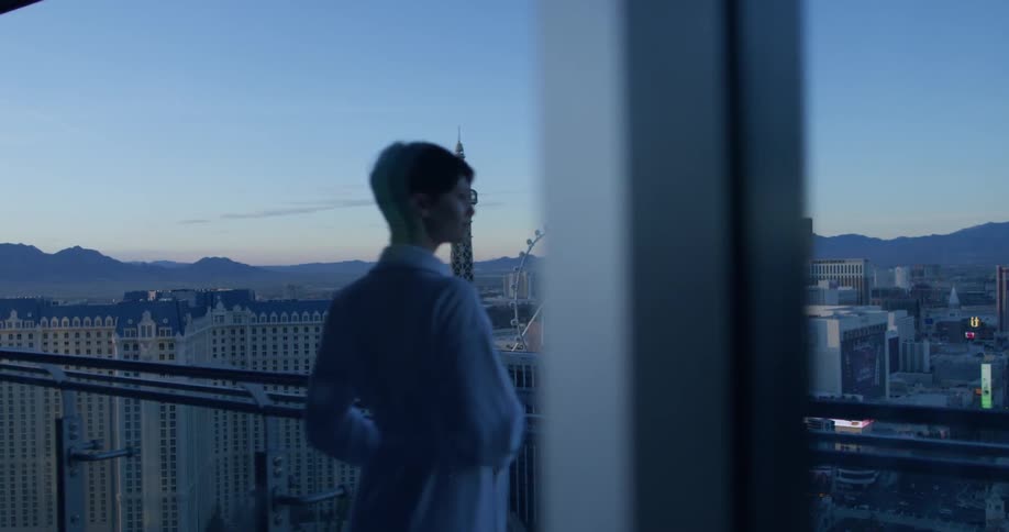 A woman is looking out over the city at sunrise