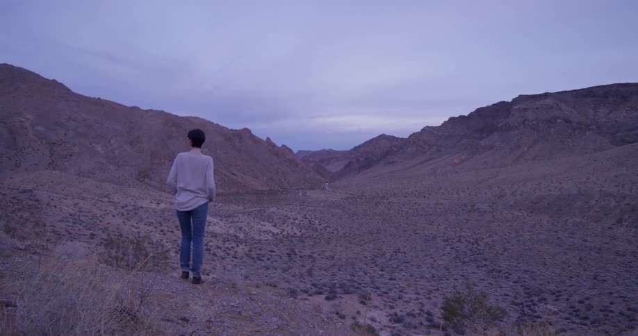 Woman stands on brushy hilly desert