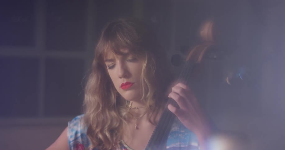 A woman plays a cello with her eyes closed