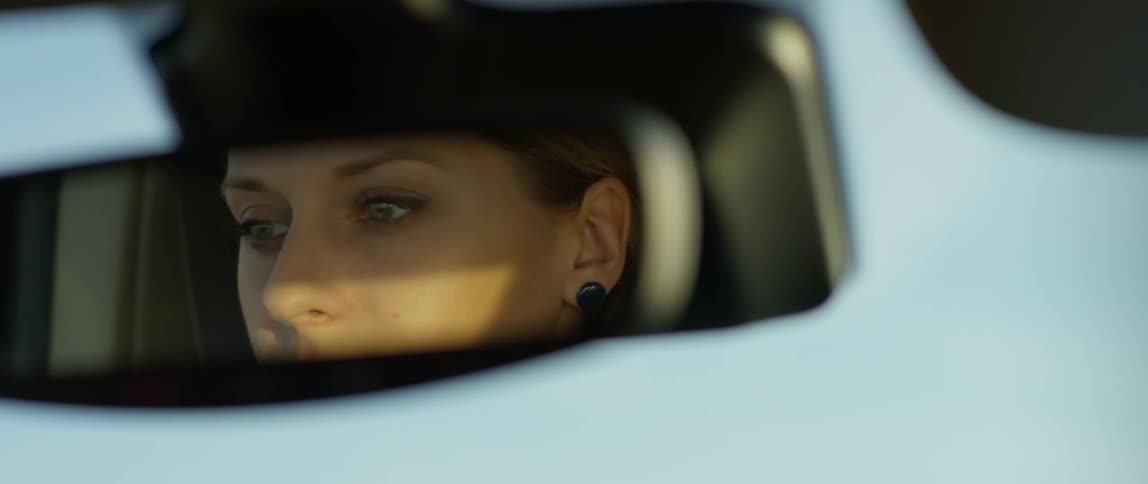 A woman drives a car on a sunny day