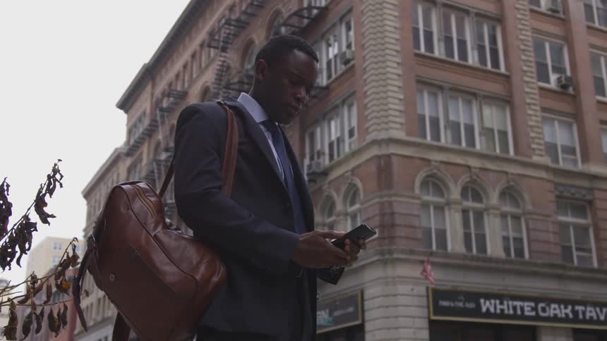 A businessman uses a phone on a city sidewalk