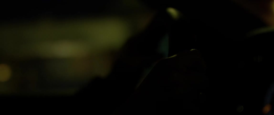 Hands grip a steering wheel while driving a car at night
