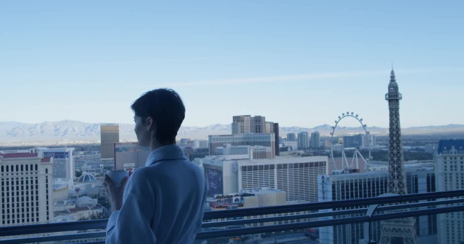 A woman enjoys a drink on her balcony
