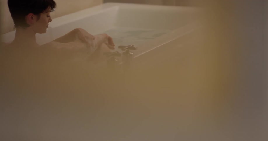 A woman washes herself while taking a bath