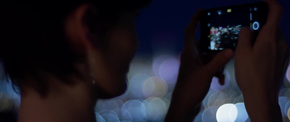 A woman photographs city lights at night