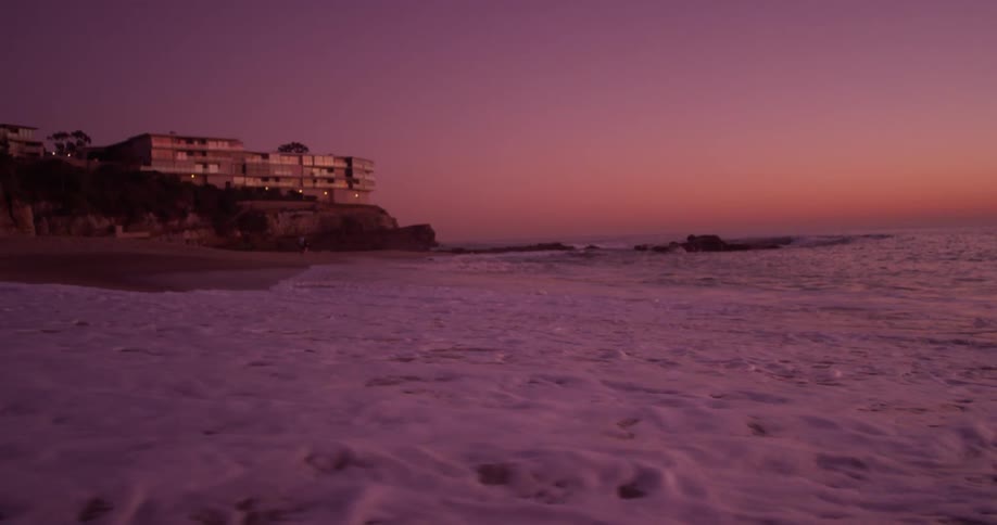 Ocean waves wash onto a beach at sunset