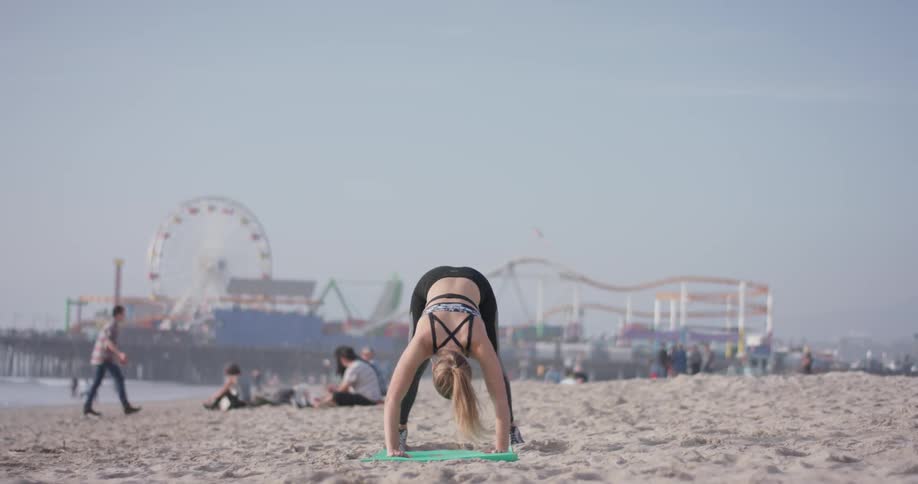 A woman is doing yoga on the beach