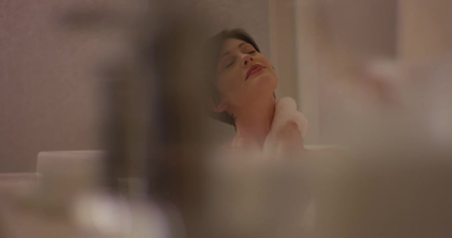 A woman washes herself while taking a bubble bath