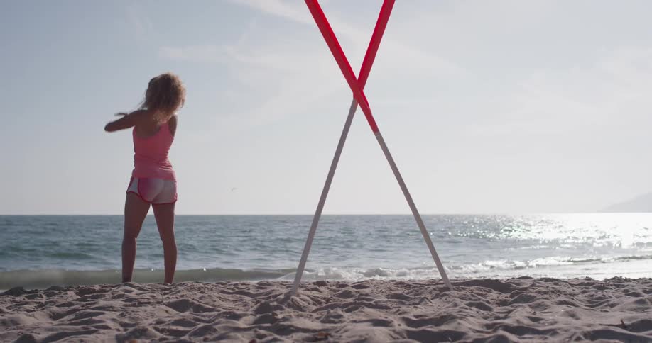 Woman hops on the beach shaking her hands and stretching