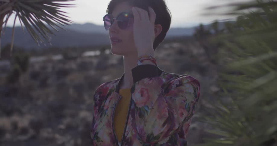 Woman stands in the desert near vegetation on a sunny day