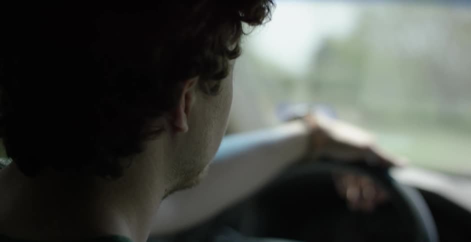 A man driving a car with one hand on the wheel
