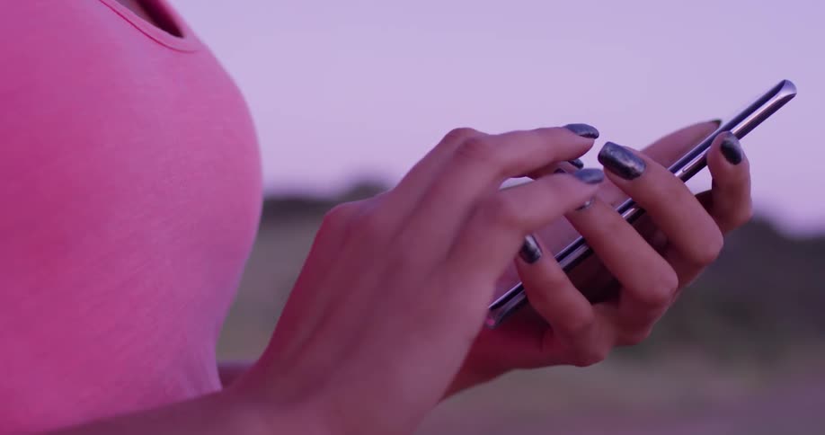 Woman stands outside scrolling and typing on her phone