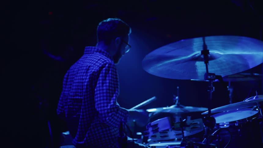 A man is playing drums in the dark