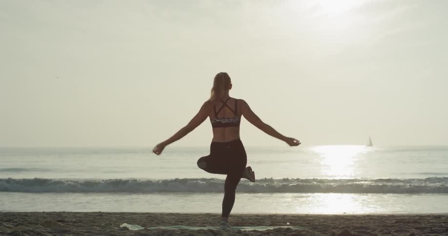 A woman does yoga on a beach