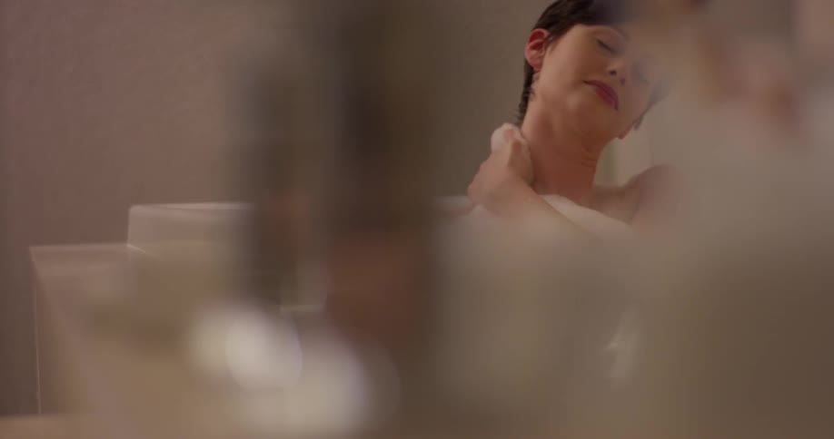 A woman washes herself while taking a bath