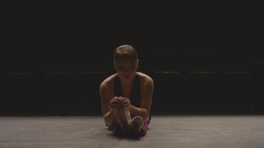 A ballerina stretches on a stage
