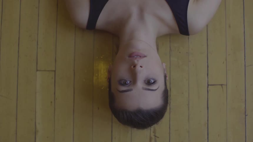 A ballerina lies on a wood floor