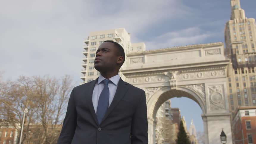 A businessman stands on a city sidewalk