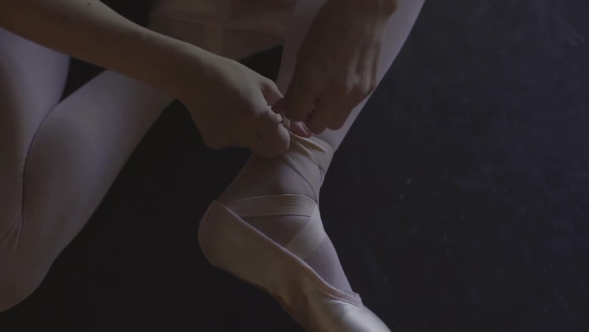 A ballerina puts on her slippers