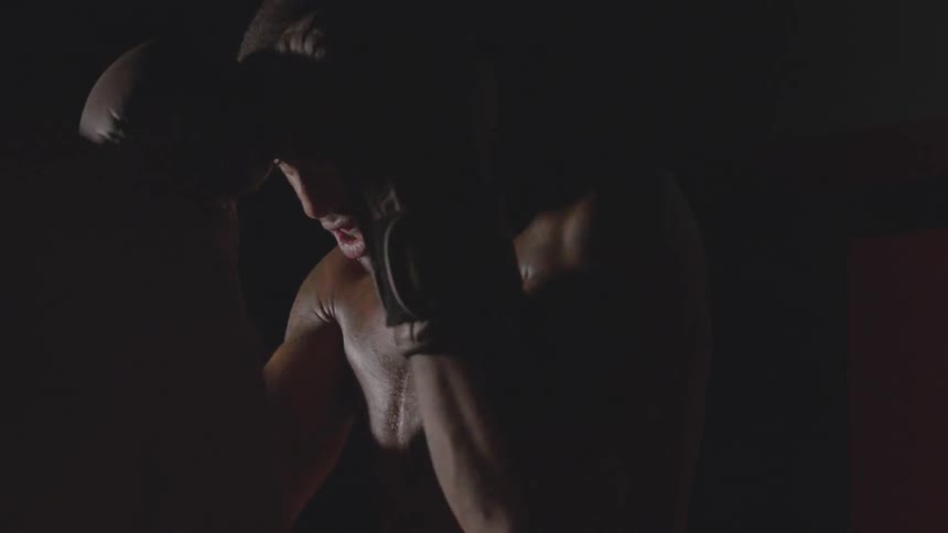 Two men box in a dim room