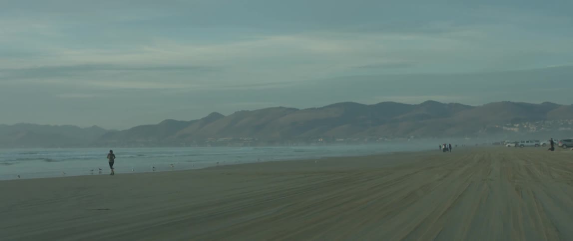 A person jogs on a sandy beach