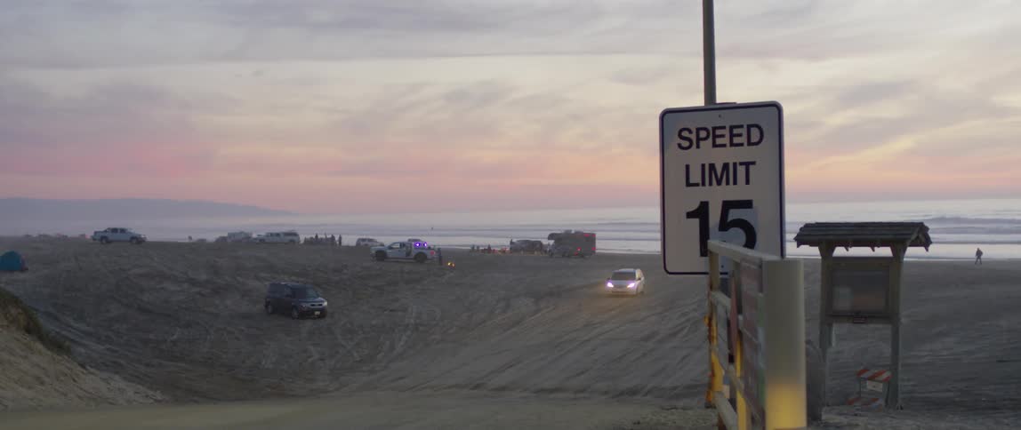 Vehicles drive on the sandy desert at sunset