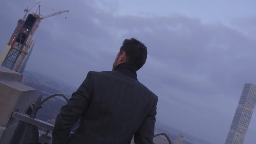 A man stands overlooking a city