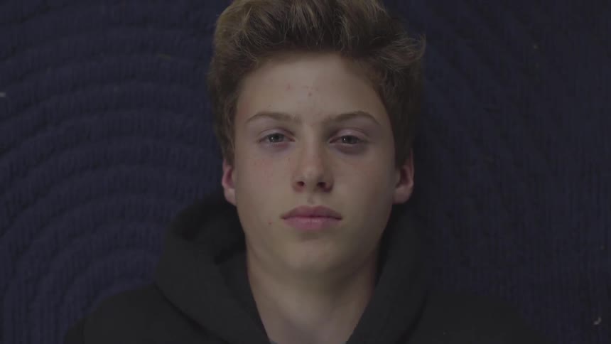 A teenager lies on a rug