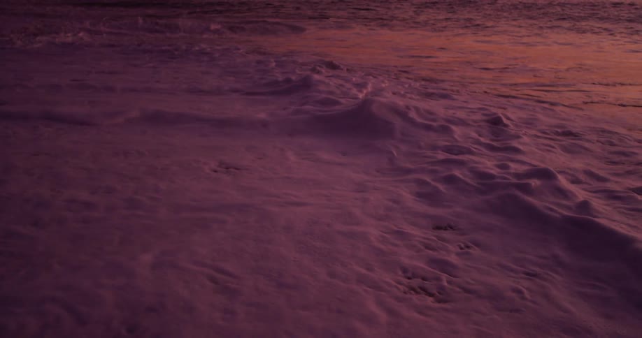 The waves slowly pull back and forth on the beach