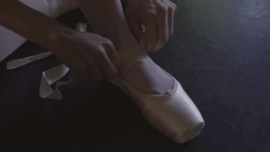 A woman puts on a ballet shoe
