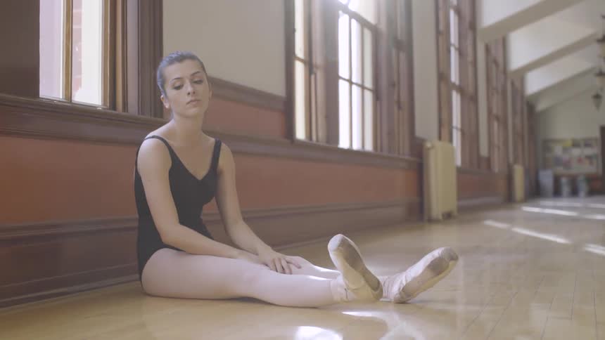 A ballerina stretches on the floor of dance studio