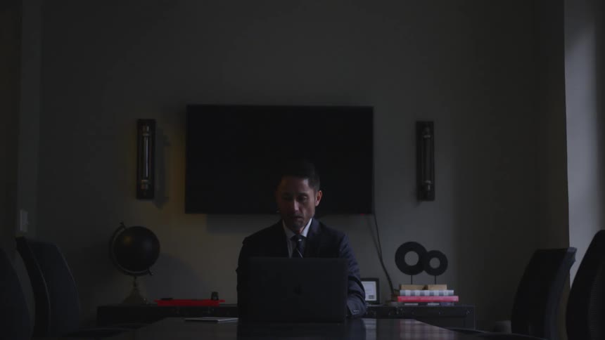 Man working on his laptop in an office with his only light source being the daylight filtering through the window