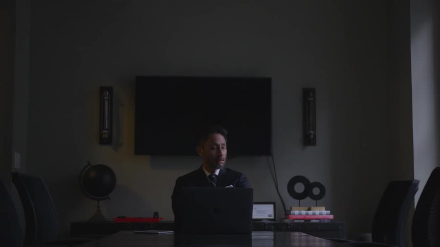 A businessman works in a dark conference room