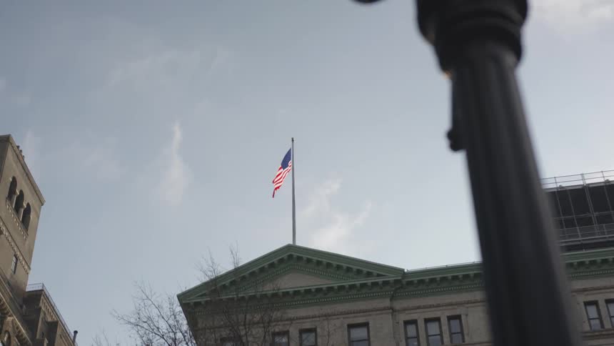 The flag blows in the wind above the building