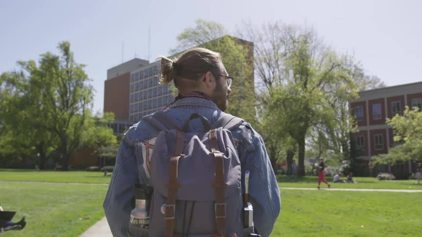 A man with a backpack walking through a park