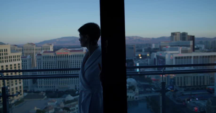 Woman opens a sliding glass door and goes out onto the balcony