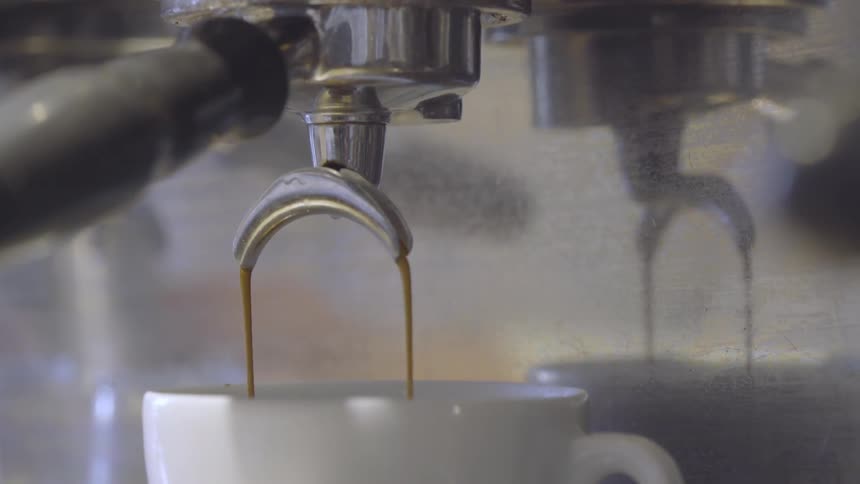 A coffee shop machine pours coffee into a cup