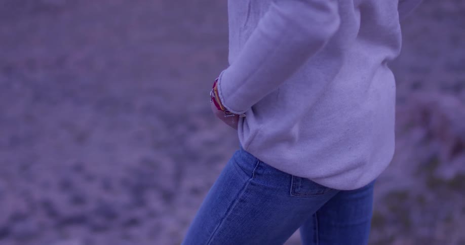 Woman wearing a white shirt and jeans stands in a field