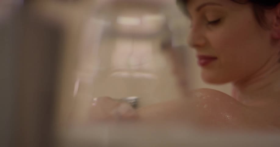 A woman cleans herself in the bathtub