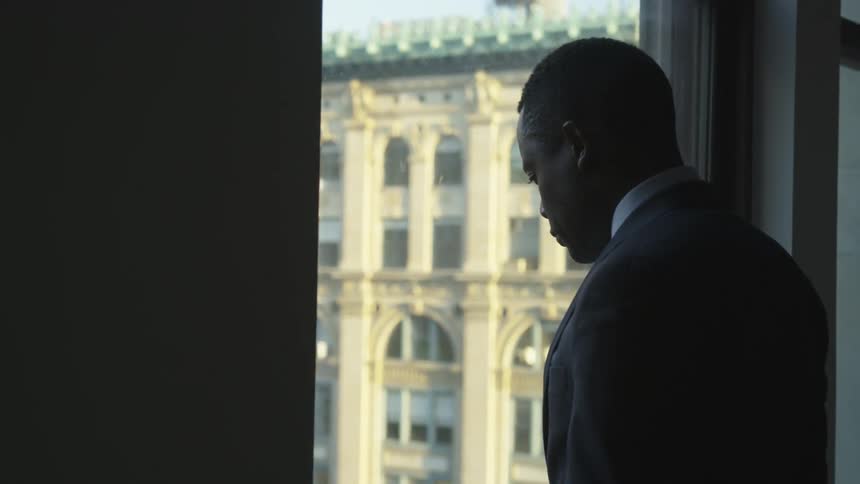 A man watches below from the window in the building