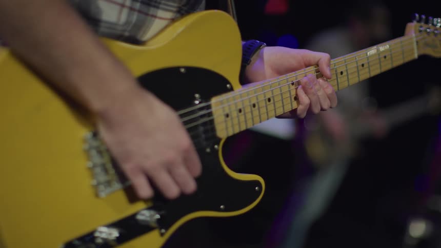 A man plays his yellow guitar