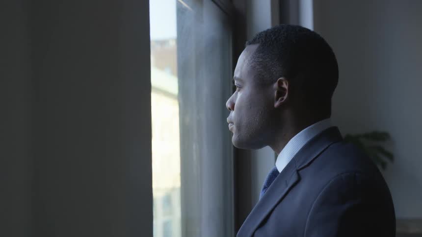 A man stands looking out the window