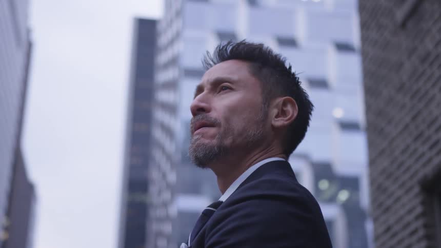 A man looks up at the tall buildings in the city