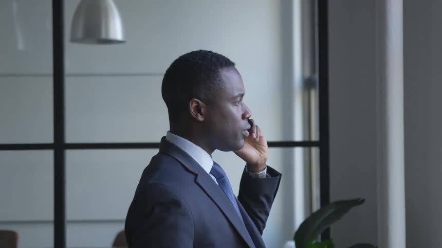Man wearing suit is talking on cell phone in building