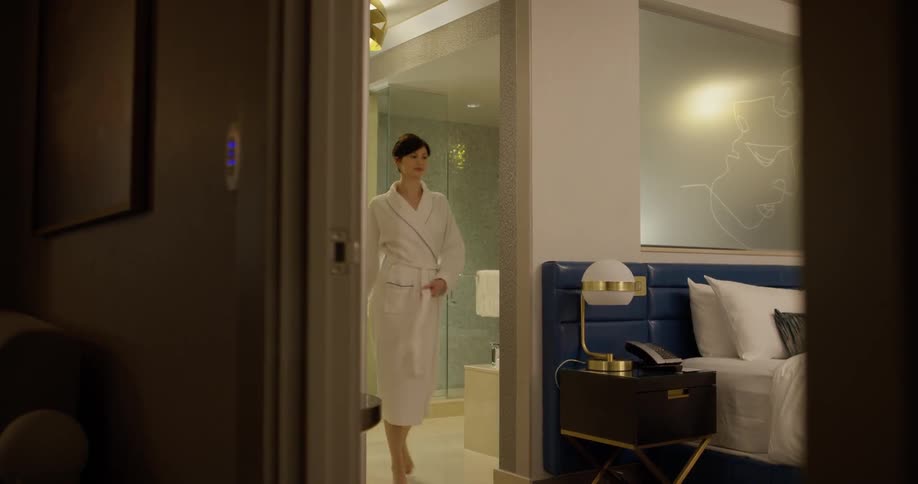 A woman wears a robe in a hotel room